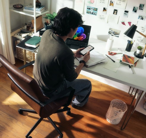 man-working-at-desk-with-laptop-and-phone-.jpg Man working at desk with laptop and phone.